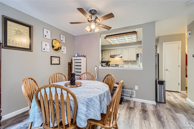 dining room featuring ceiling fan, light hardwood / wood-style floors, and a textured ceiling