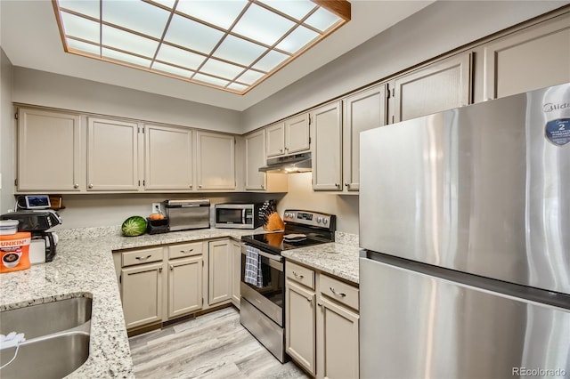 kitchen featuring light stone counters, stainless steel appliances, and light hardwood / wood-style floors