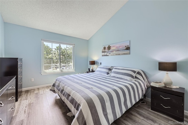 7370 E Florida Ave Unit 1020, Denver, CO 80231 - bedroom featuring wood finished floors, vaulted ceiling, baseboards, and a textured ceiling