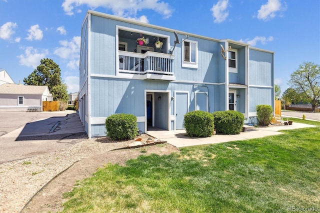 view of front of house with a balcony and a front lawn