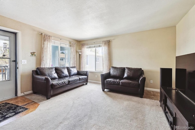 living area with carpet floors, baseboards, and a textured ceiling