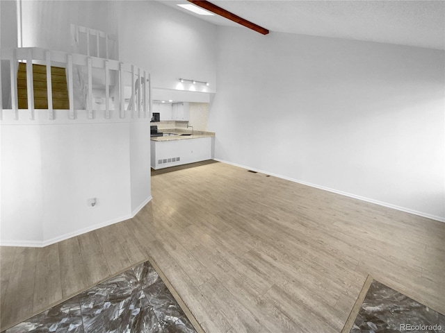 unfurnished living room with lofted ceiling with beams and hardwood / wood-style flooring