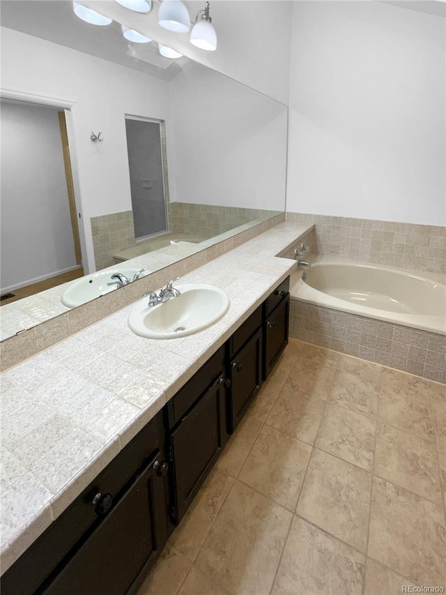 bathroom featuring vanity, a relaxing tiled tub, and tile patterned floors