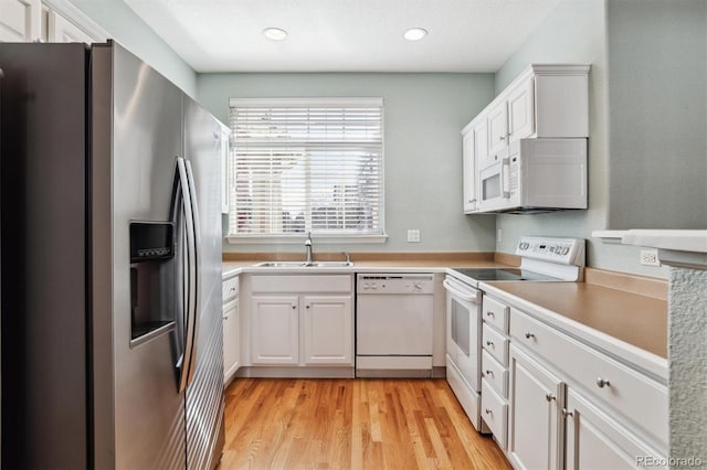 kitchen featuring white appliances, light hardwood / wood-style floors, sink, and white cabinets