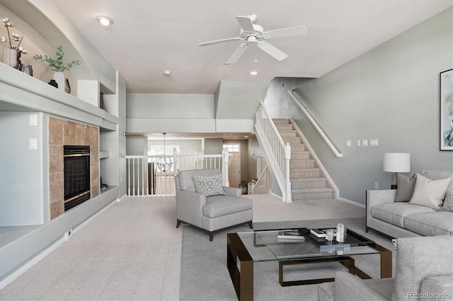 carpeted living room with a textured ceiling, a tile fireplace, and ceiling fan