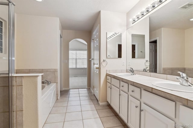 bathroom with tile patterned flooring, a bath, and vanity