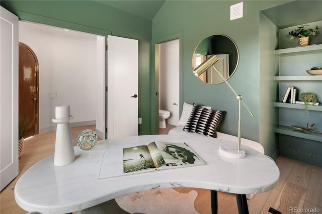 bathroom featuring toilet, vaulted ceiling, and hardwood / wood-style flooring