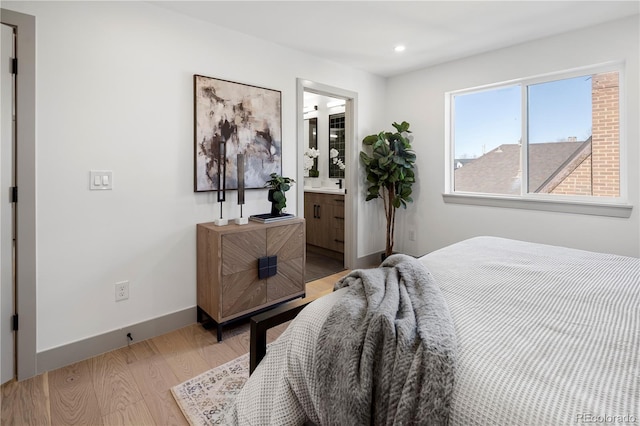 bedroom with light hardwood / wood-style floors and ensuite bathroom