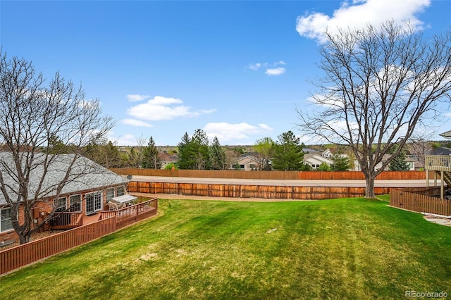 view of yard featuring a deck, a residential view, and a fenced backyard