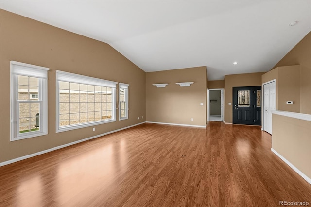 unfurnished living room featuring baseboards, wood finished floors, and lofted ceiling