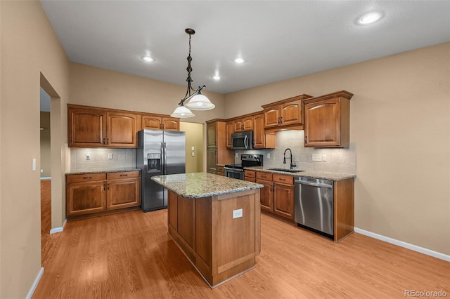 kitchen featuring decorative backsplash, light wood-type flooring, brown cabinets, a sink, and stainless steel appliances