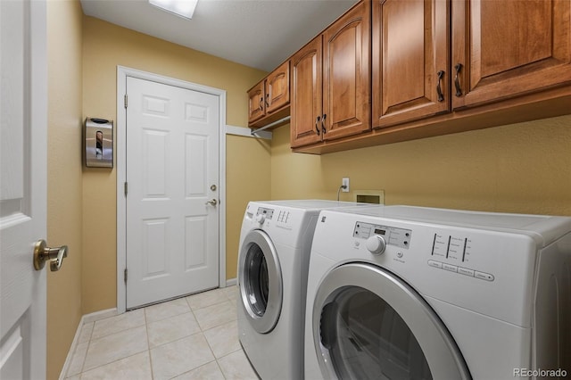 laundry room featuring baseboards, cabinet space, light tile patterned floors, and washing machine and dryer