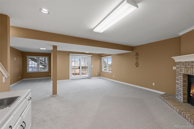 basement with plenty of natural light, light carpet, and a brick fireplace