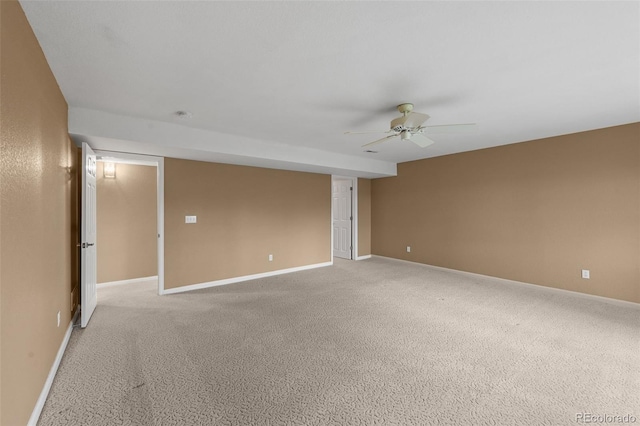 spare room featuring ceiling fan, light colored carpet, and baseboards
