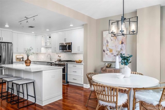 1631 N Emerson St Unit 117, Denver, CO 80218 - kitchen with a chandelier, stainless steel appliances, a kitchen bar, dark wood-style flooring, and visible vents
