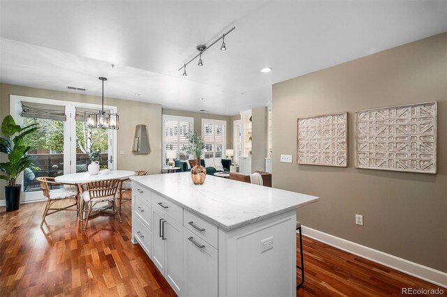1631 N Emerson St Unit 117, Denver, CO 80218 - kitchen with white cabinets, a breakfast bar, wood finished floors, rail lighting, and a kitchen island