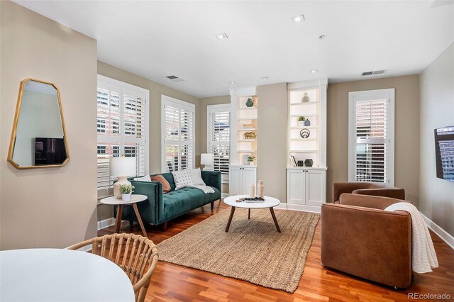 1631 N Emerson St Unit 117, Denver, CO 80218 - living area featuring baseboards, built in features, wood finished floors, and visible vents