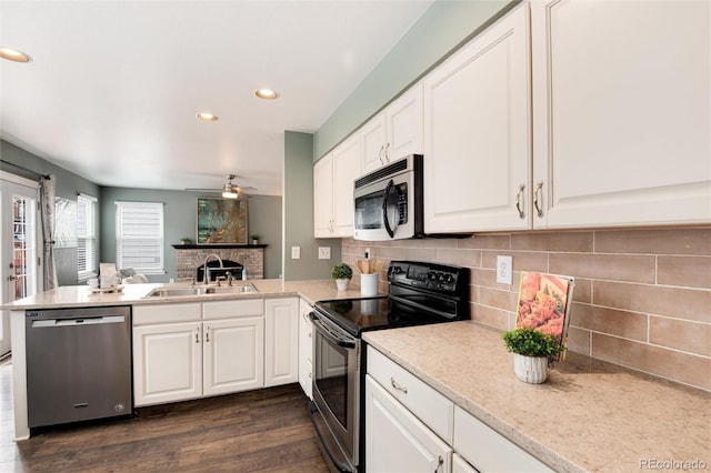 kitchen with a ceiling fan, a peninsula, a sink, appliances with stainless steel finishes, and white cabinetry