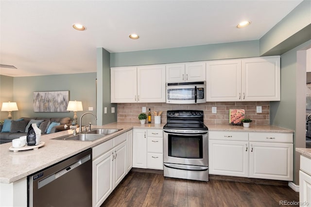 kitchen featuring a peninsula, dark wood-style flooring, a sink, stainless steel appliances, and open floor plan