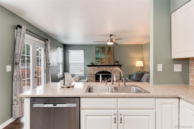 kitchen with a sink, a fireplace, open floor plan, and stainless steel dishwasher