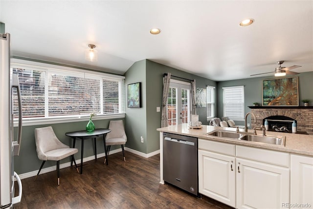 kitchen featuring dark wood finished floors, a sink, white cabinets, appliances with stainless steel finishes, and a brick fireplace