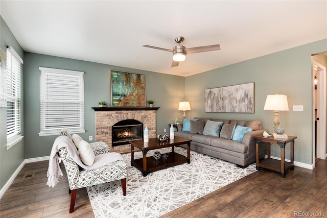 living room with visible vents, baseboards, a fireplace, wood finished floors, and a ceiling fan