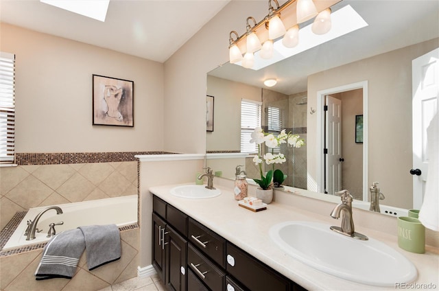 bathroom featuring a tile shower, a skylight, and a sink