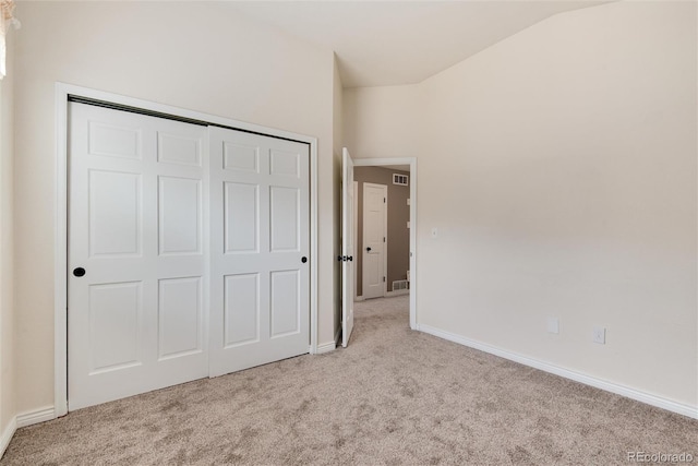 unfurnished bedroom featuring vaulted ceiling, carpet flooring, baseboards, and a closet