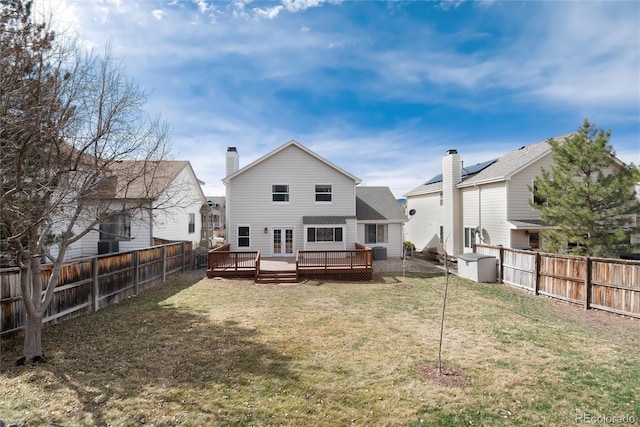 back of property featuring a chimney, a fenced backyard, a lawn, and a wooden deck