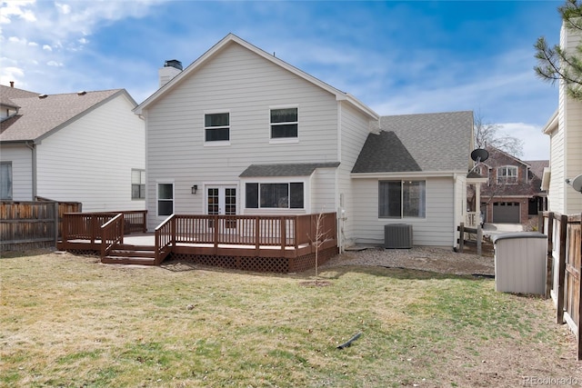 back of property with a deck, fence, and a lawn