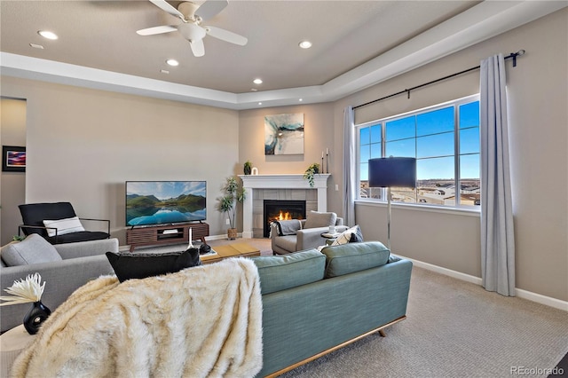 living area featuring carpet, baseboards, recessed lighting, a tile fireplace, and a raised ceiling