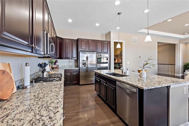 kitchen featuring visible vents, dark wood-type flooring, an island with sink, a sink, and appliances with stainless steel finishes