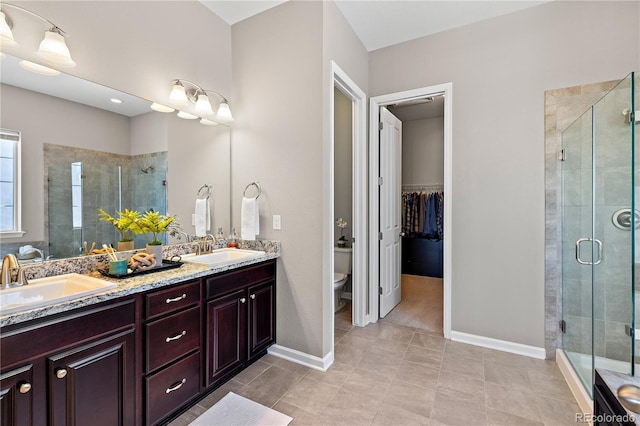 bathroom with double vanity, a stall shower, toilet, and a sink