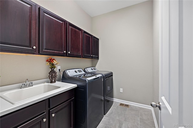 clothes washing area featuring baseboards, visible vents, cabinet space, a sink, and washing machine and dryer