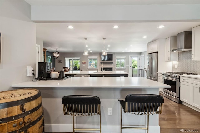 3040 S Dexter Way, Denver, CO 80222 - kitchen with premium appliances, wall chimney range hood, a breakfast bar area, a peninsula, and recessed lighting