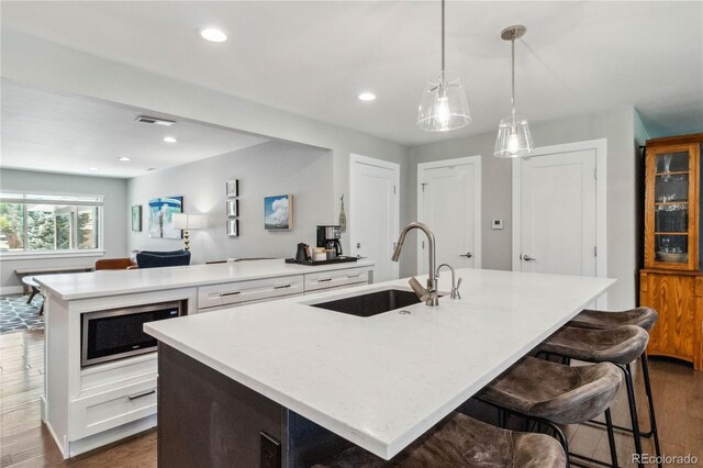 3040 S Dexter Way, Denver, CO 80222 - kitchen featuring an island with sink, a sink, dark wood-style floors, white cabinets, and recessed lighting