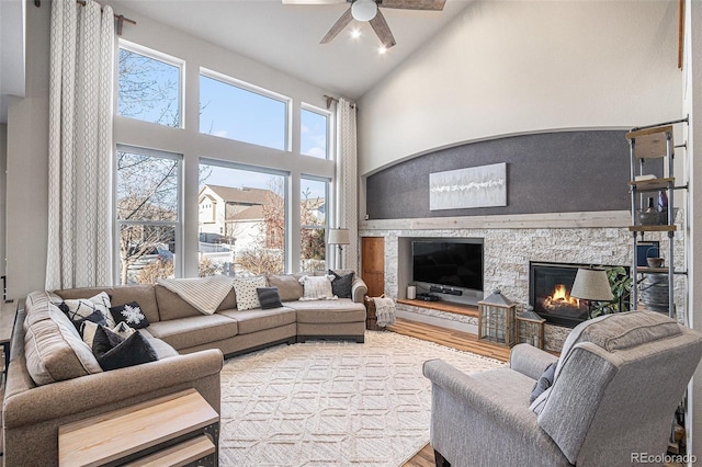 living area with ceiling fan, high vaulted ceiling, a fireplace, and wood finished floors