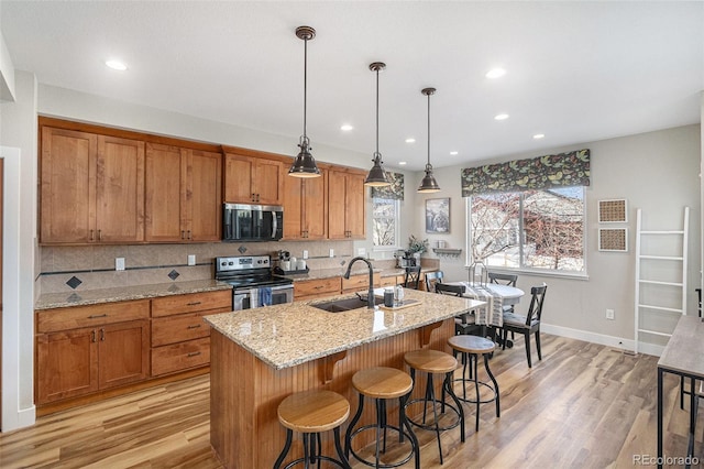 kitchen with brown cabinetry, decorative backsplash, stainless steel appliances, and a sink