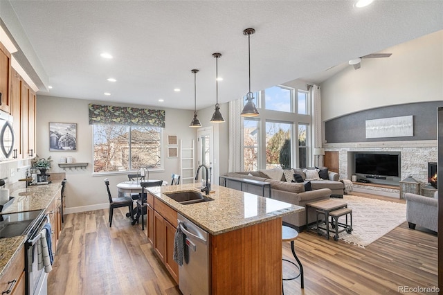 kitchen with wood finished floors, appliances with stainless steel finishes, brown cabinetry, and a sink