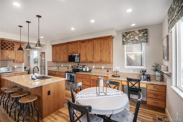 kitchen featuring an island with sink, light wood-type flooring, stainless steel appliances, and a sink