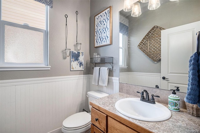 bathroom featuring a wainscoted wall, vanity, and toilet