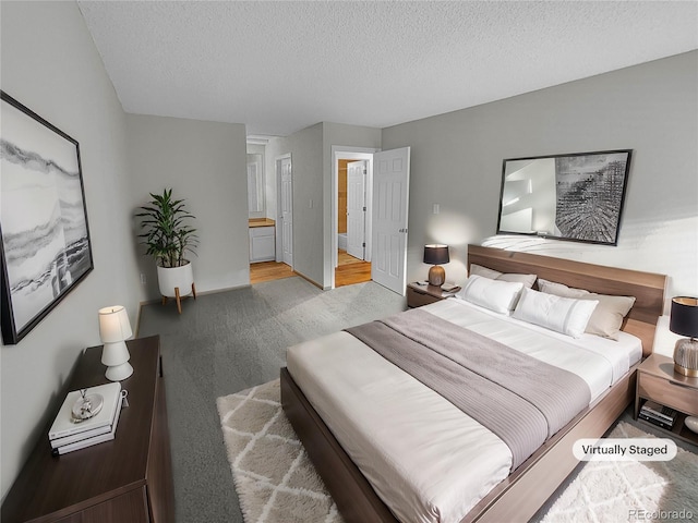 bedroom featuring light colored carpet, ensuite bath, and a textured ceiling