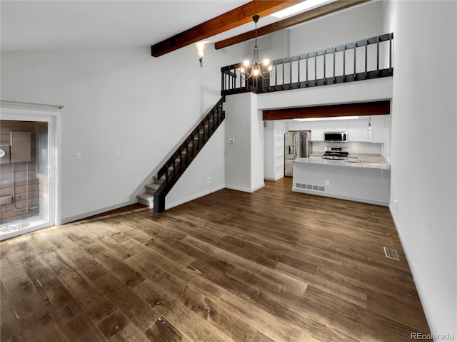 unfurnished living room with dark wood-type flooring, a towering ceiling, beam ceiling, and a notable chandelier