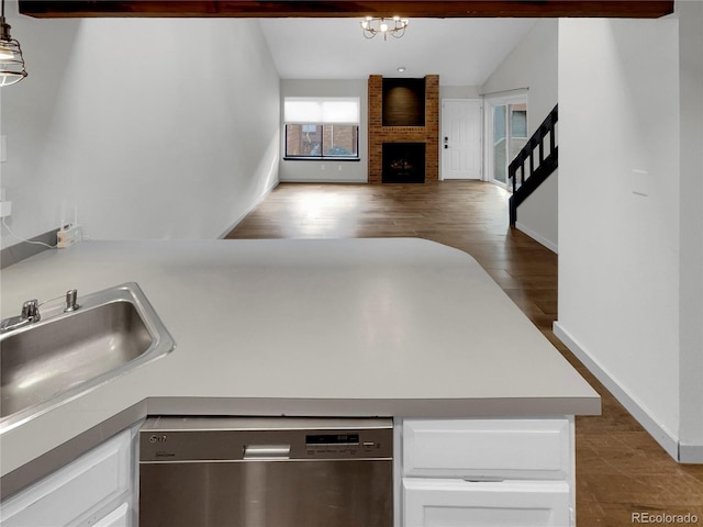 kitchen with a fireplace, white cabinetry, dishwasher, hanging light fixtures, and beam ceiling