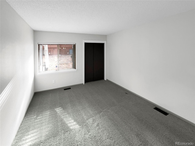 carpeted spare room with a textured ceiling