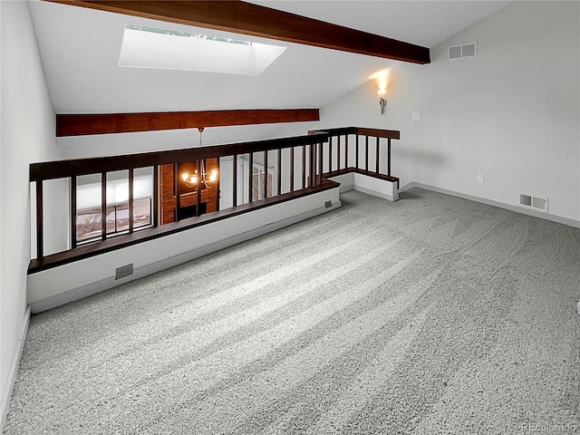 carpeted spare room featuring vaulted ceiling with skylight and an inviting chandelier