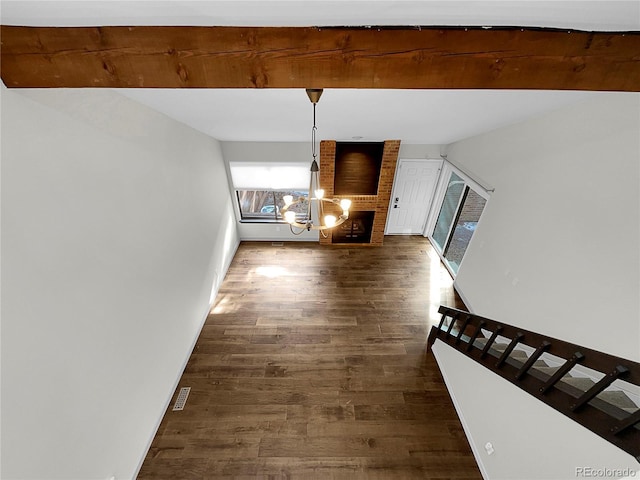 unfurnished living room with a brick fireplace, dark wood-type flooring, and beam ceiling