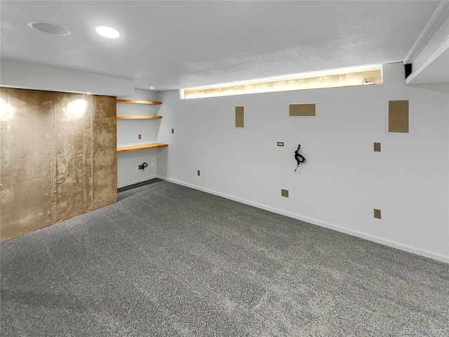 basement featuring dark carpet and a textured ceiling