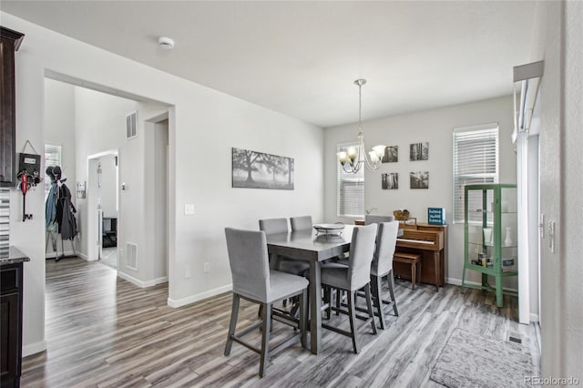 dining room featuring visible vents, light wood-style flooring, baseboards, and a chandelier