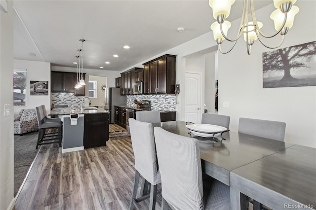 dining room with an inviting chandelier, recessed lighting, and dark wood-style flooring